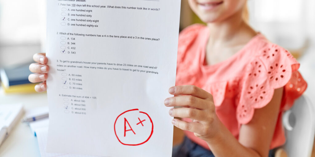 little girl holding up a test showing A+