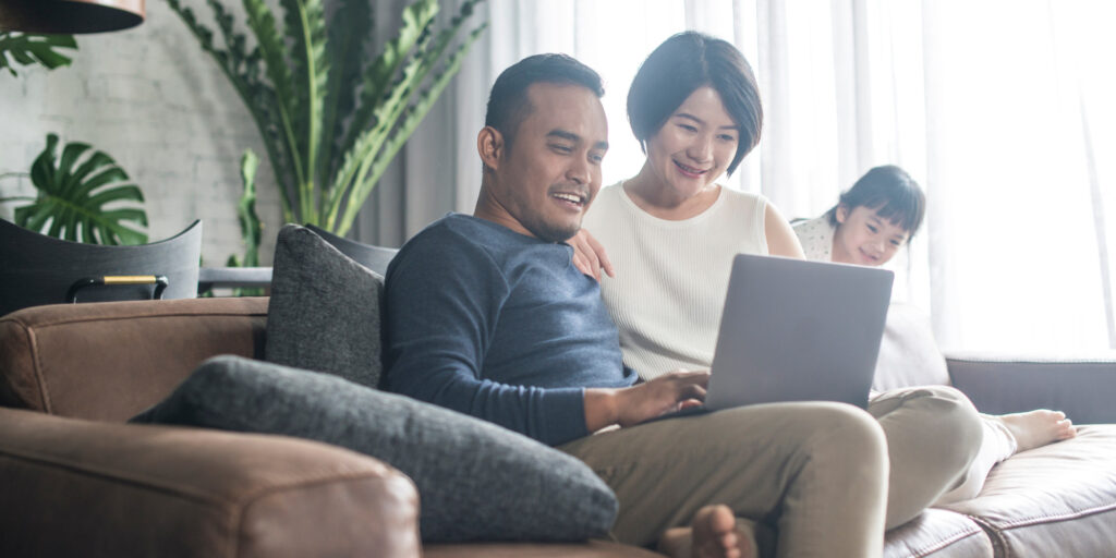family sitting on a couch looking at a computer