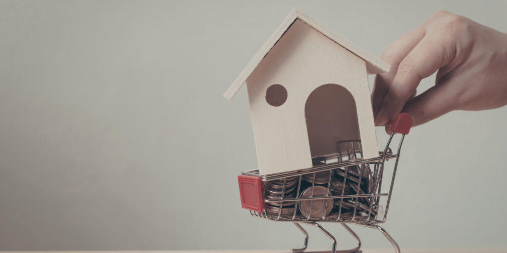 mini shopping cart with coins in it and mini house in the cart