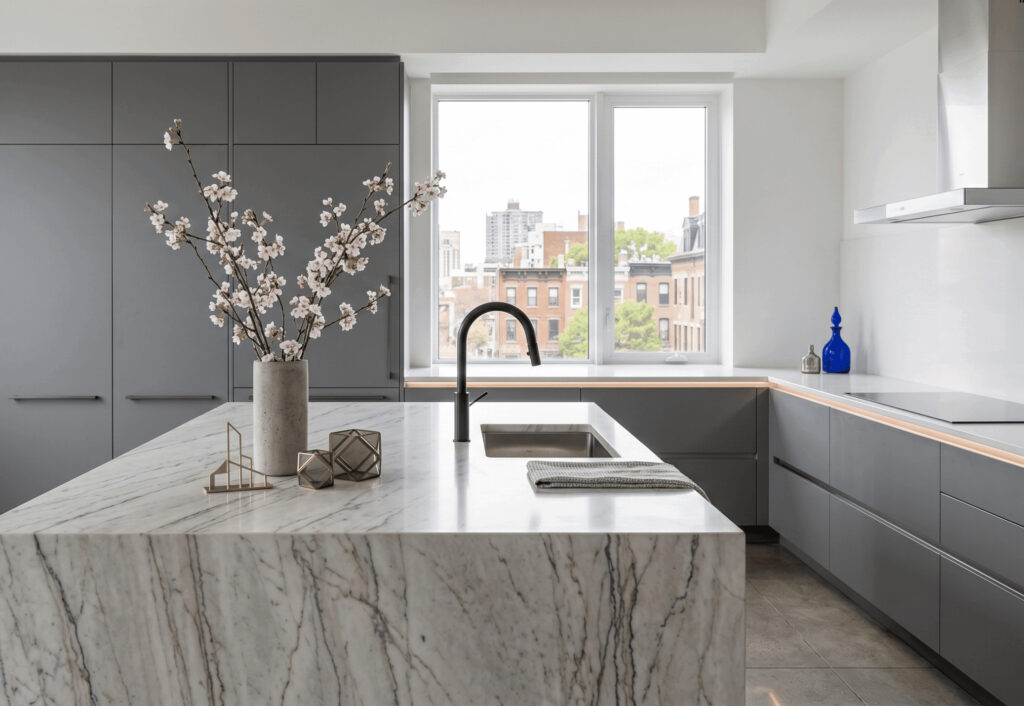 A close-up of a high-end modern kitchen featuring white marble countertops and minimalist decor.